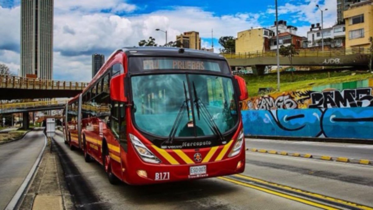 Bus de TransMilenio, color rojo, rodando por la calle 