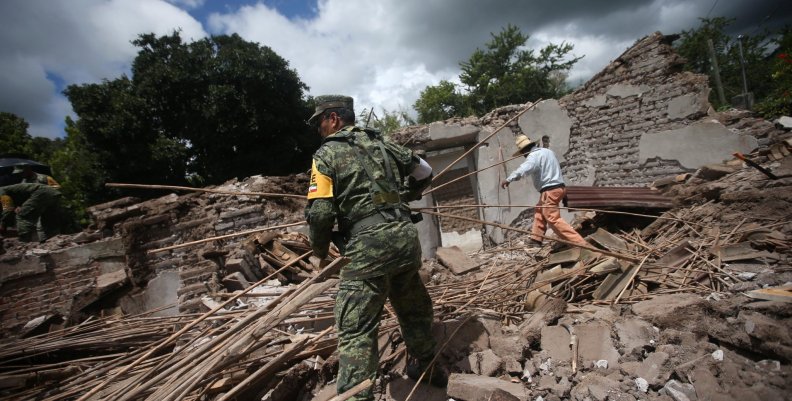 A soldier and a resident clear rubble from a destroyed house after an earthquake in San Juan Pilcaya, at the epicenter zone A soldier and a resident clear rubble from a destroyed house after an earthquake in San Juan Pilcaya, at the epicenter zone