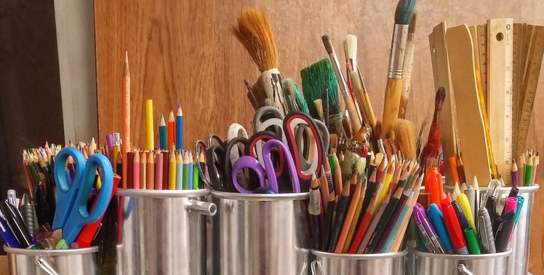 Útiles escolares Tarros de metal llenos de diversos implementos escolares