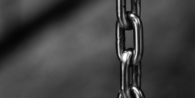 Cadenas Cadena gris colgando sobre un fondo oscuro