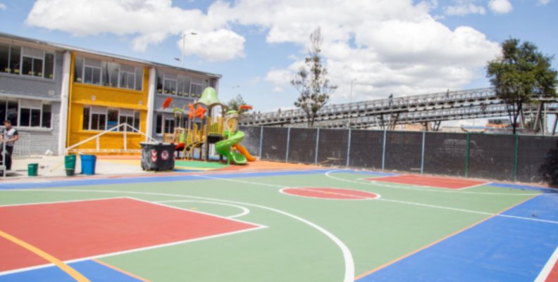 Colegios en Bogotá Patio principal de un colegio de Bogotá con una cancha de microfútbol pintada de verde, rojo y azul.