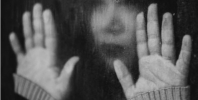 Depresión Mujer con las manos frente a una ventana empapada en blanco y negro