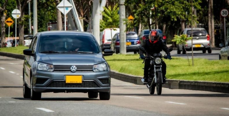 Impuesto vehicular Carro gris y moto negra sobre la carretera