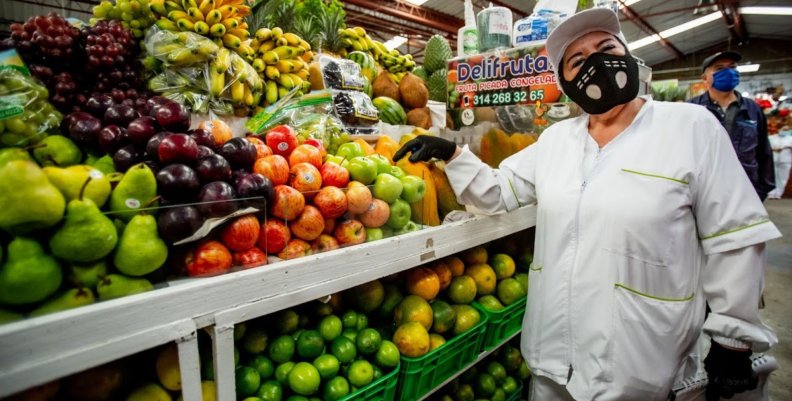 Alimentos en Bogotá Mujer al lado de una despensa con frutas