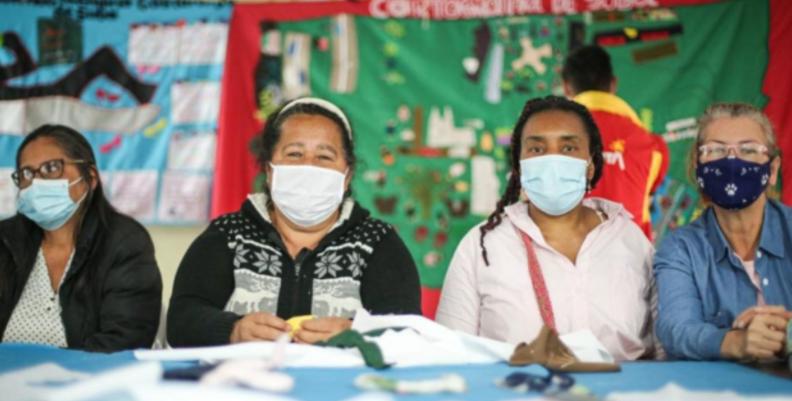 Cuatro mujeres mayores sentadas en una mesa de tejido