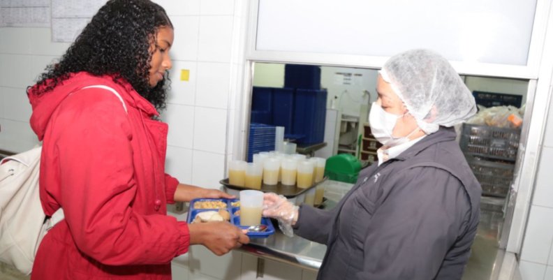 PAE en Bogotá Una mujer sirviendo un plato de comida a otra