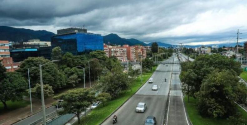 Carretera con pocos carros transitando y rodeada de árboles