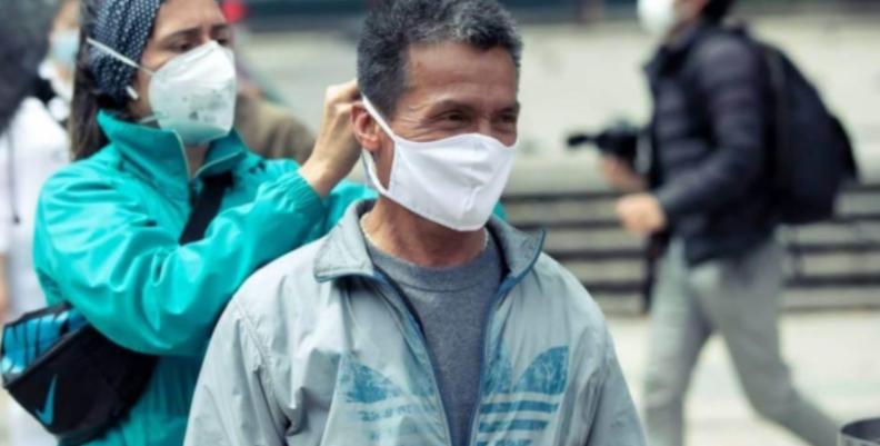 Mujer poniéndole un tapabocas a un hombre de mediana edad