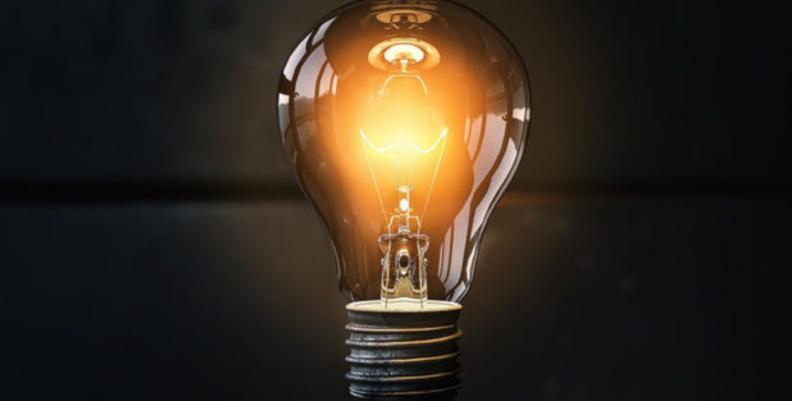 Bombilla de luz encendida en un fondo negro