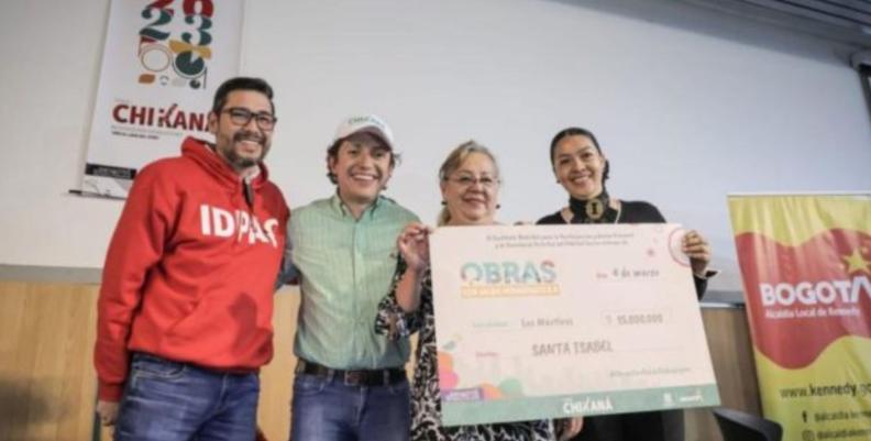 Funcionarios de la Alcaldía de Bogotá junto a beneficiarias del Fondo Chikaná, que sostienen un cheque en sus manos