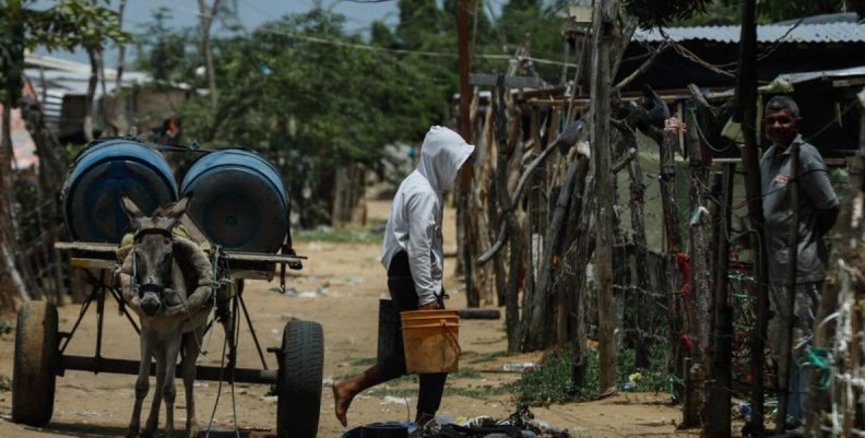 Pobreza multidimensional Un hombre cargando unos bidones de agua