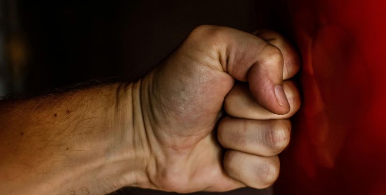 Justicia por mano por mano propia Un puño golpeando una pared roja