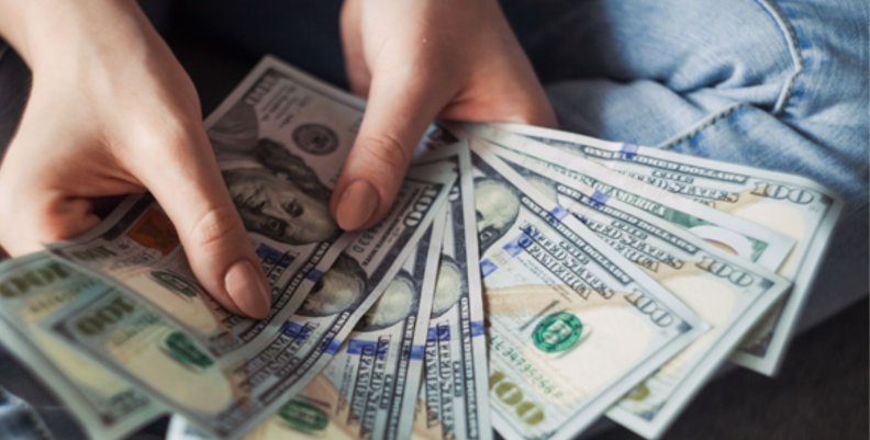 Dólar Unas manos sostienen entre ocho y nueve billetes de un dólar