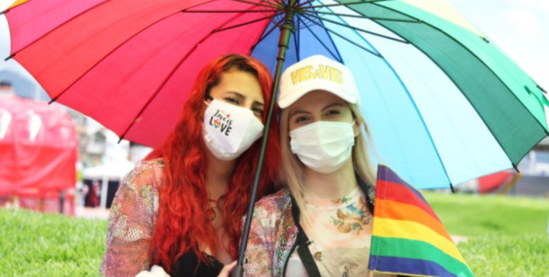 Festival Lesbiarte Dos mujeres con tapabocas y bajo una sombrilla miran a la cámara