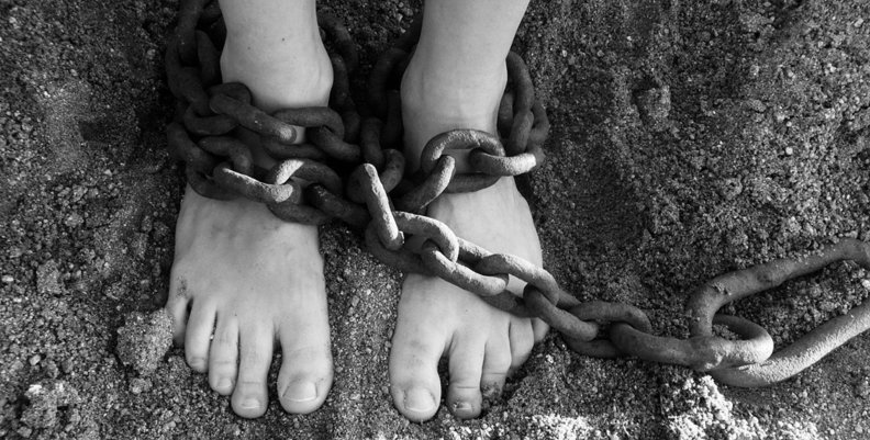 Abuso sexual infantil Piernas sobre arena, rodeadas de una cadena