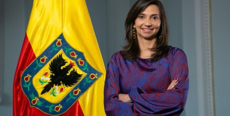 Finanzas de Bogotá Mujer parada al lado de una bandera de Bogotá