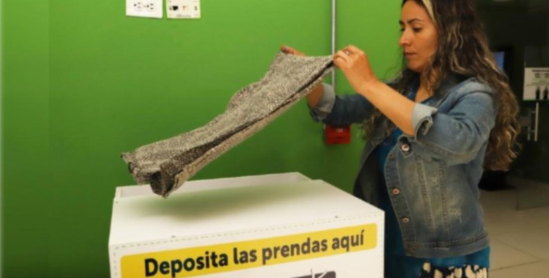 Donación de ropa Mujer dobla una muda de ropa sobre una de las cajas dispuestas para las donaciones