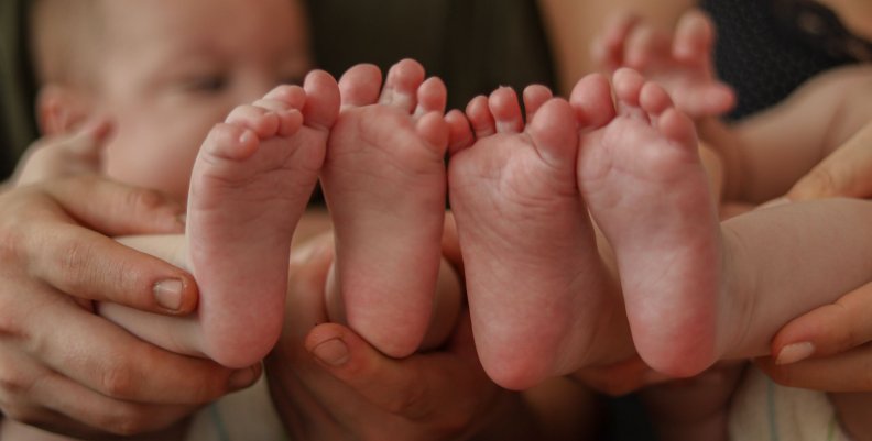 Adopción Pies de dos bebés al lado de sus padres