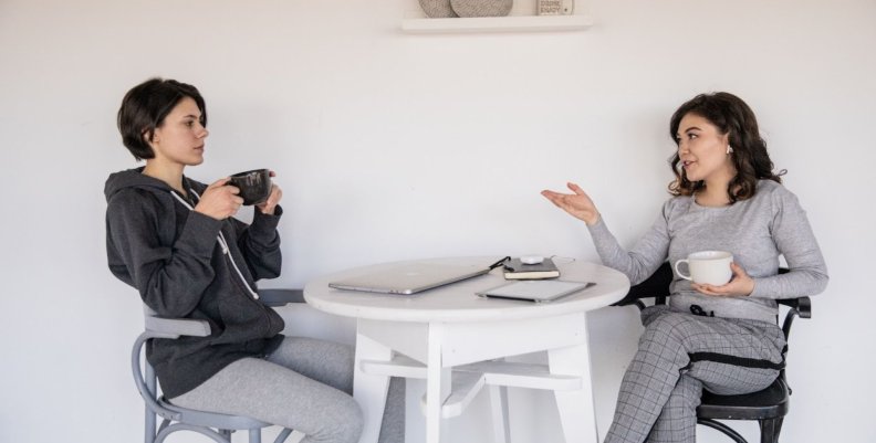 Reconciliación Dos mujeres conversando en una mesa mientras toman un café