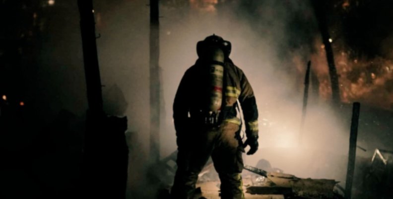 Bomberos. Bombero de espaldas frente a una conflagración recién apagada.