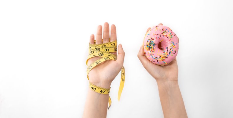 Obesidad infantil en Colombia un problema para la salud y la economía Manos de un niño sosteniendo una dona y un medidor.