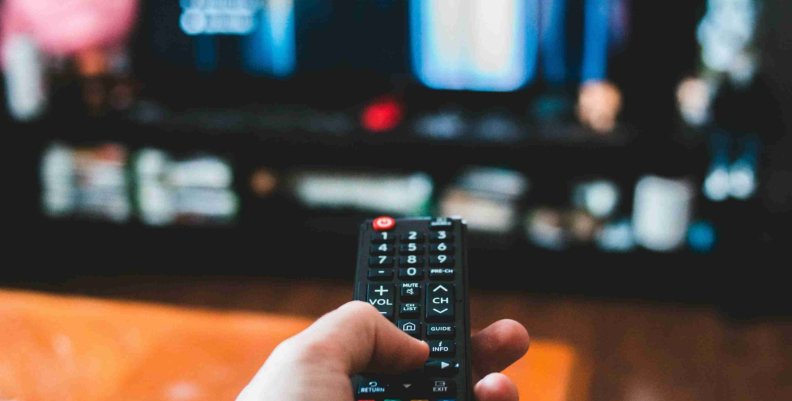 TDT Una persona con un control remoto en la mano a punto de cambiar algo en su televisor
