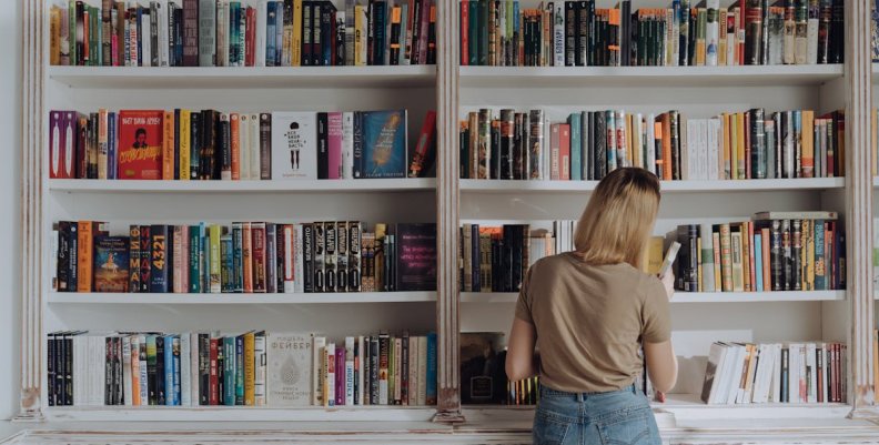 Escritores bogotanos en la FILBo 2025 Mujer frente a una estante lleno de libros