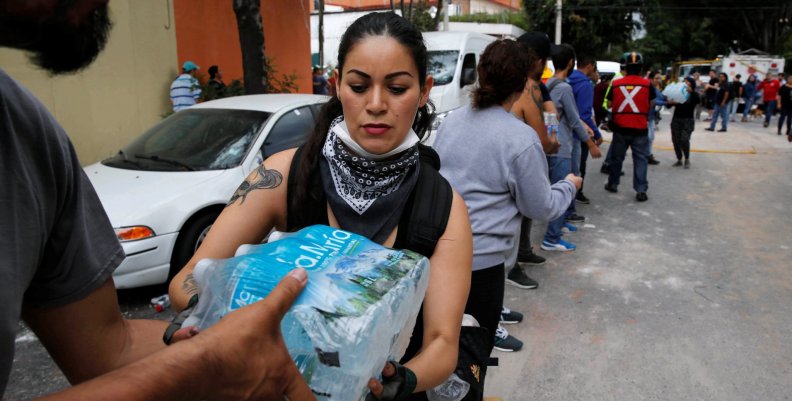People carry donations of bottled water for rescue workers and victims next to at a collapsed building after earthquake in Mexico City People carry donations of bottled water for rescue workers and victims next to at a collapsed building after earthquake in Mexico City