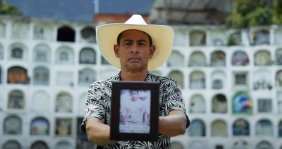Hombre sosteniendo una foto de una persona frente a cámara