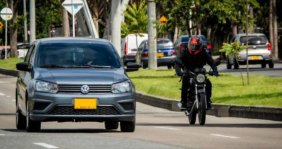 Un carro y una moto rodando en una calle