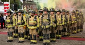 Una fila de hombres en marcha con uniformes de bombero