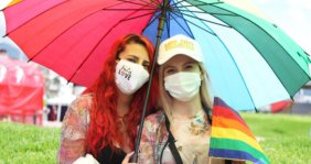 Dos mujeres con tapabocas y bajo una sombrilla miran a la cámara