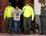 Juan Carlos Mesa Vallejo, also known as "Tom", is escorted by police officers during a press presentation at the Police headquarters in Medellin