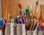 Tarros de metal llenos de diversos implementos escolares