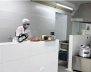 Mujer vestida con traje de cocinera al lado de una estufa de un comedor comunitario