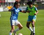 Dos mujeres con uniformes de fútbol disputando un balón 