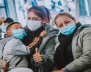 Mujeres con tapabocas. Una lleva en brazos a un niño
