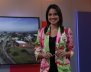 Mujer sonriente con blazer color rosa sobre un fondo morado