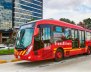 Bus de TransMilenio, color rojo, rodando por la calle 