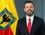 Foto del alcalde Carlos Fernando Galán con traje negro, delate de una bandera de Bogotá