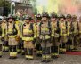 Una fila de hombres en marcha con uniformes de bombero