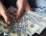 Unas manos sostienen entre ocho y nueve billetes de un dólar