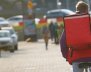 Domiciliario transitando en bicicleta por la ciudad con una mochila cuadrada de color naranja