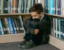 Niño triste en un rincón de un escaparate con libros