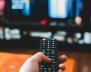Una persona con un control remoto en la mano a punto de cambiar algo en su televisor