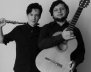 Dos hombres, uno con guitarra y otro con una flauta traversa