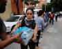 People carry donations of bottled water for rescue workers and victims next to at a collapsed building after earthquake in Mexico City