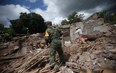 A soldier and a resident clear rubble from a destroyed house after an earthquake in San Juan Pilcaya, at the epicenter zone