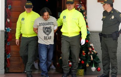 Juan Carlos Mesa Vallejo, also known as "Tom", is escorted by police officers during a press presentation at the Police headquarters in Medellin