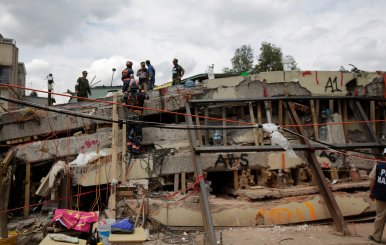 Members of a rescue team search for students amidst the rubble of a collapsed building of the  Enrique Rebsamen school after an earthquake in Mexico City